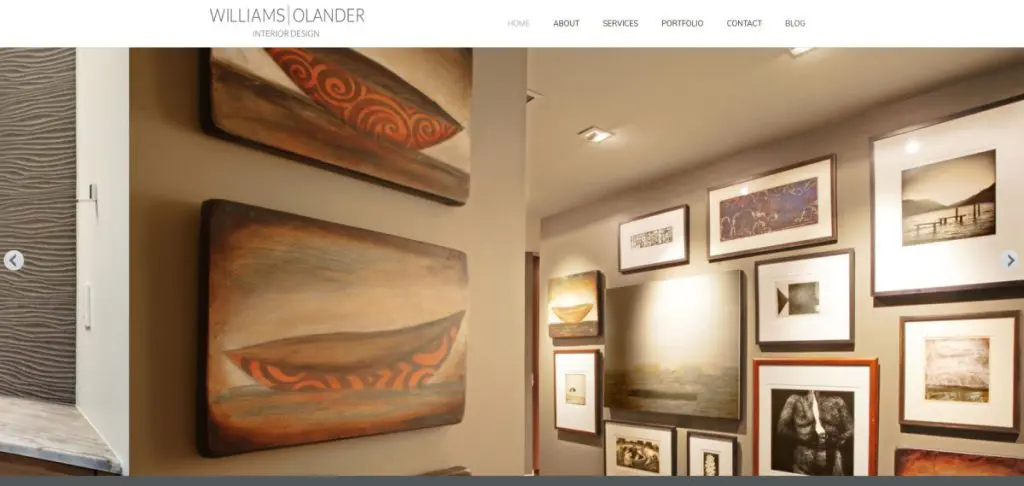 Hallway wall displaying various framed artworks and photographs, with two larger paintings of boats on the adjacent wall—like a curated web design portfolio—enhanced by modern interior lighting.