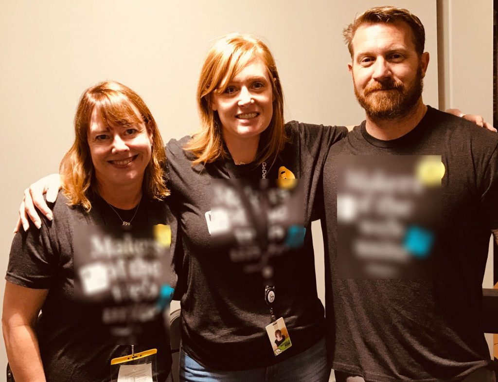 Three people posing for a photo wearing GoDaddy t-shirts.