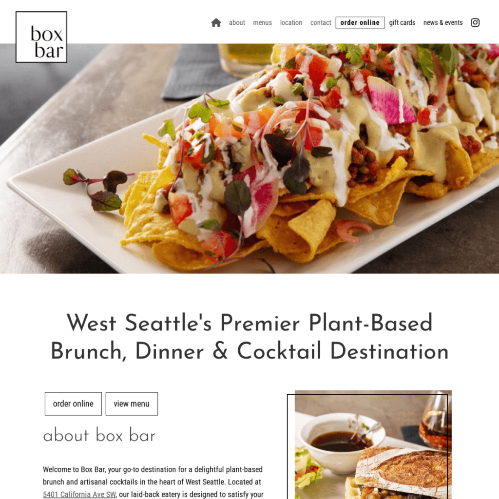 A plate of nachos topped with plant-based cheese, chickpeas, diced tomatoes, onions, herbs, and sauce sits on a table at Box Bar restaurant—perfect inspiration for any creative Web Design Portfolio.