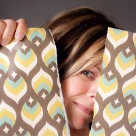 A person with a partially visible face holds two torn pieces of patterned paper that fit together to form a whole design, reminiscent of the creative synergy often seen in Seattle Market web design.