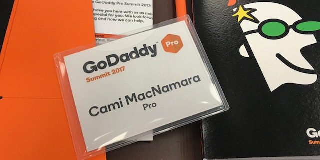 A notebook featuring an orange cover and a pen positioned on top, used during the GoDaddy Pro Summit 2017.