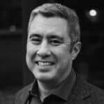 Smiling man with short gray hair, wearing a collared shirt and blazer, shown in a black and white portrait photo—the image captures the professional presence of a West Seattle web designer.