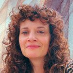 A West Seattle web designer with curly hair smiles at the camera against a textured background.