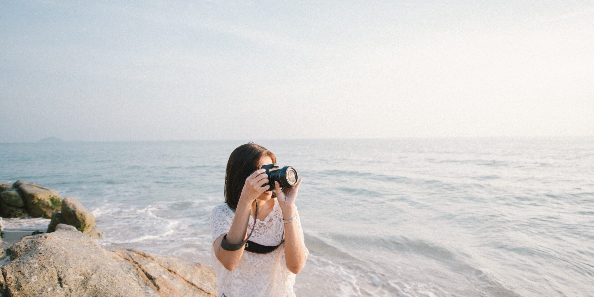 A woman capturing the mesmerizing ocean view with her camera, contributing to the collection of stock images.